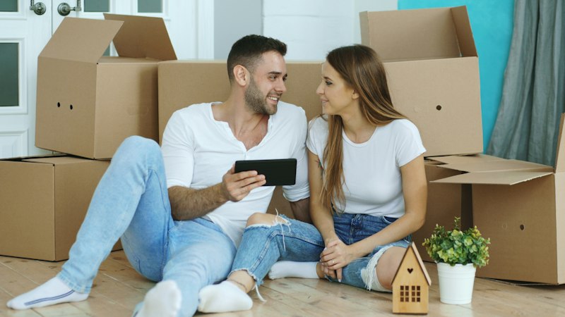 Couple looking at phone surrounded by moving boxes